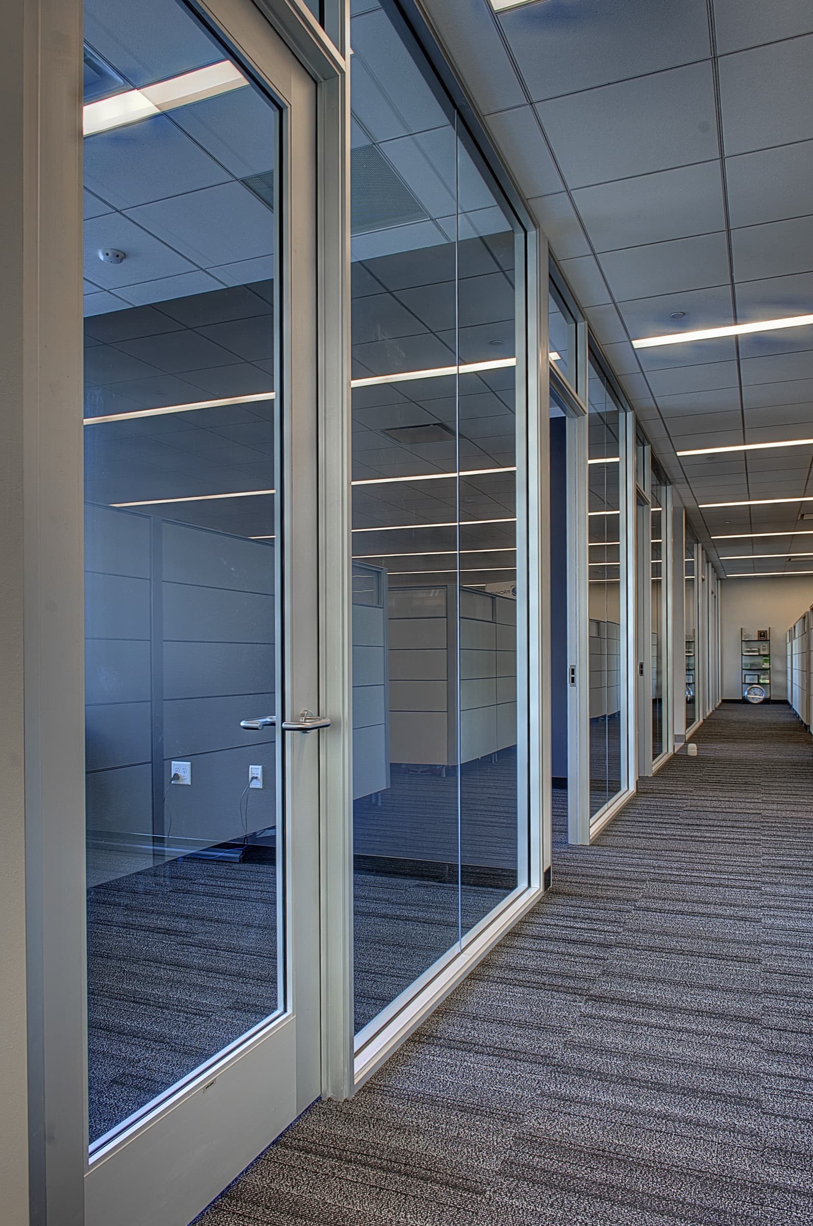 Office corridor lined with aluminum-framed glass doors and side lites